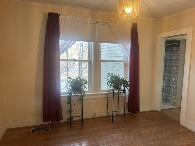 interior space with hardwood / wood-style floors, visible vents, crown molding, baseboards, and a notable chandelier