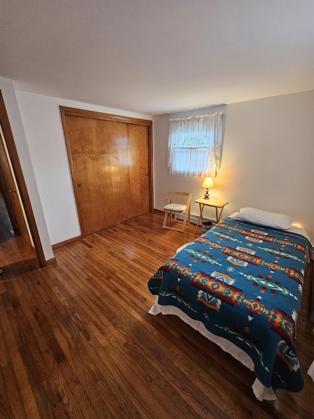 bedroom with wood finished floors, a closet, and baseboards