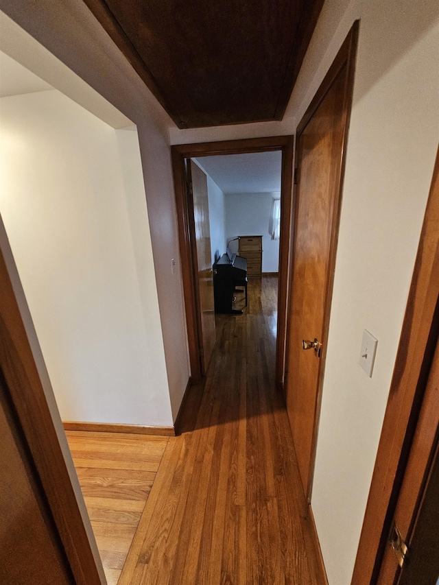 hallway with dark wood finished floors and baseboards