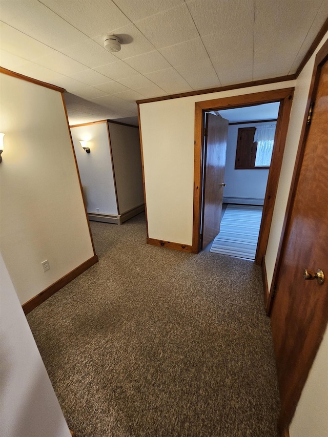 hallway with a baseboard radiator, baseboards, ornamental molding, and carpet flooring