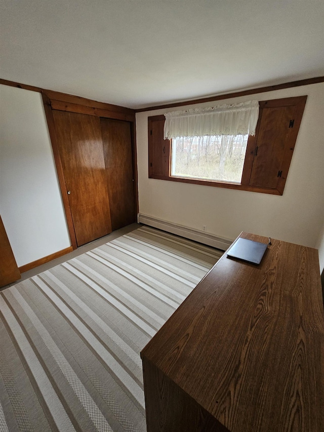 unfurnished bedroom with baseboard heating and a closet