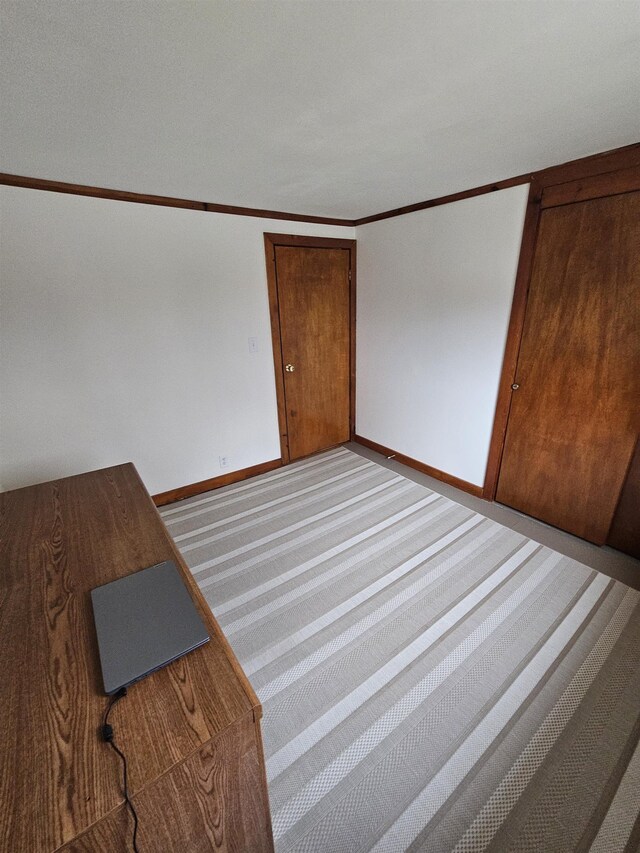 empty room featuring baseboards, ornamental molding, and carpet