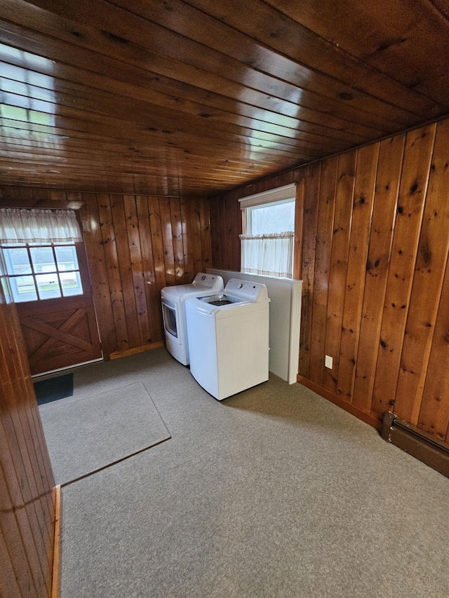 clothes washing area featuring wooden walls, washer and clothes dryer, laundry area, and plenty of natural light