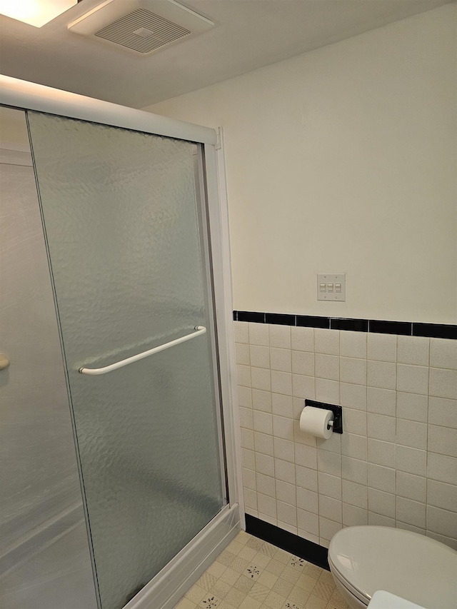 bathroom with tile walls, visible vents, a shower stall, and toilet
