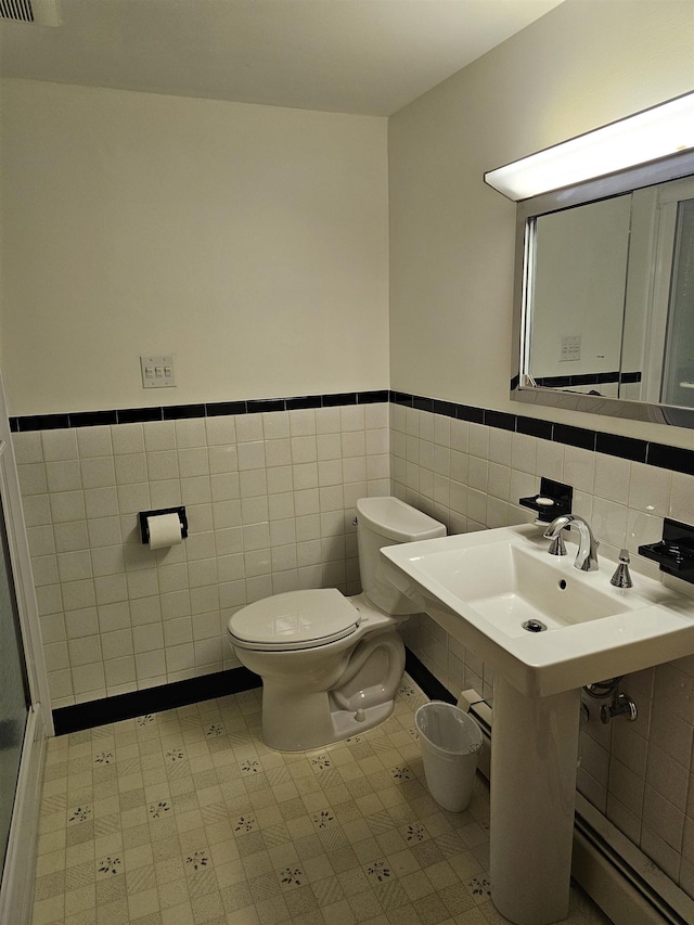 bathroom featuring tile walls, tile patterned floors, a wainscoted wall, and toilet