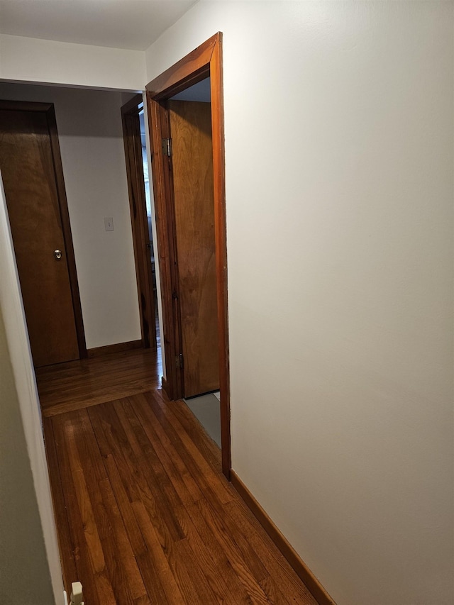 corridor featuring wood finished floors and baseboards