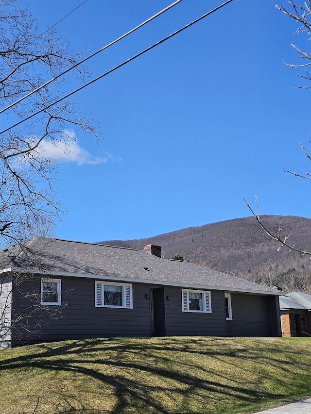 ranch-style house with a chimney, a front lawn, and a mountain view
