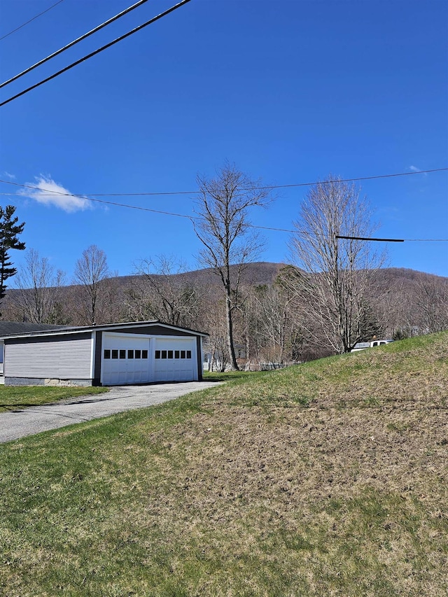 view of yard with aphalt driveway, a mountain view, and a garage