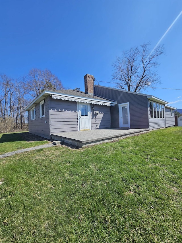 back of house with a chimney and a yard