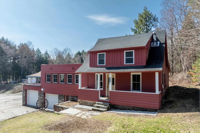 view of front of house with a shingled roof, board and batten siding, driveway, a porch, and a garage