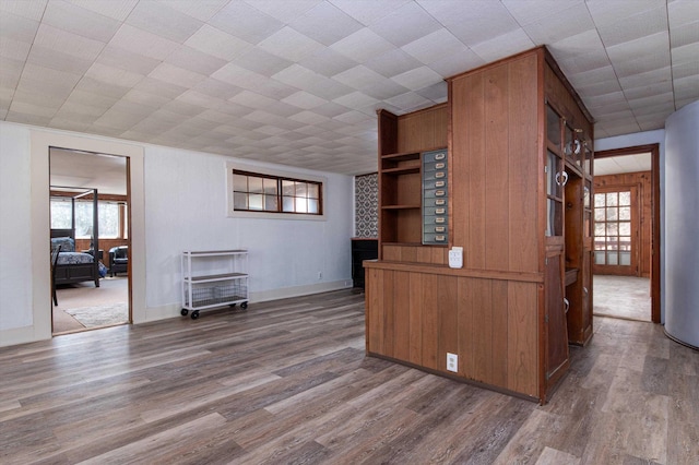 unfurnished living room with a wealth of natural light, wood finished floors, and baseboards