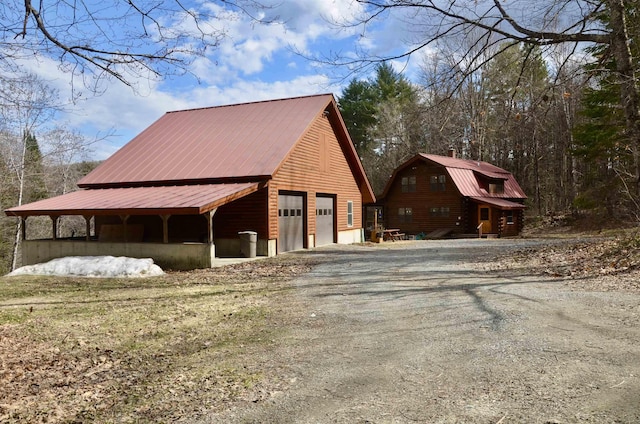 view of home's exterior with a detached garage, a gambrel roof, a chimney, and metal roof
