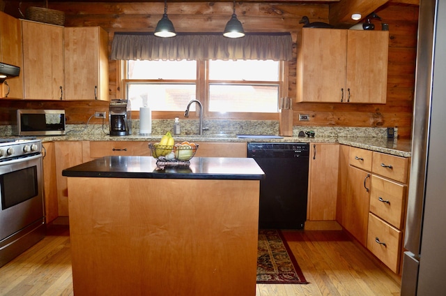 kitchen with a sink, plenty of natural light, light wood finished floors, appliances with stainless steel finishes, and a kitchen island