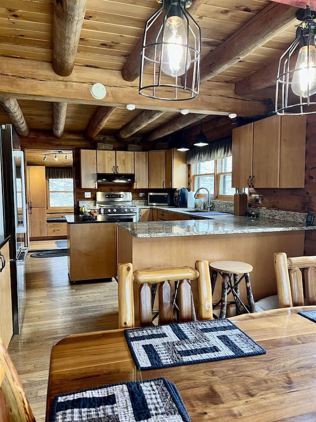 kitchen featuring a peninsula, stainless steel appliances, beamed ceiling, wood finished floors, and wood ceiling