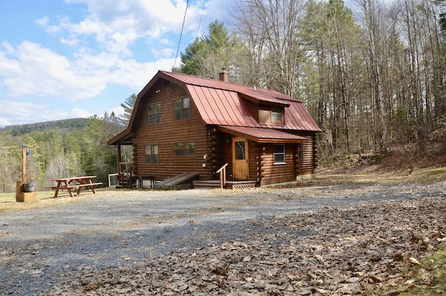 view of front of property featuring a gambrel roof, log siding, a standing seam roof, and metal roof