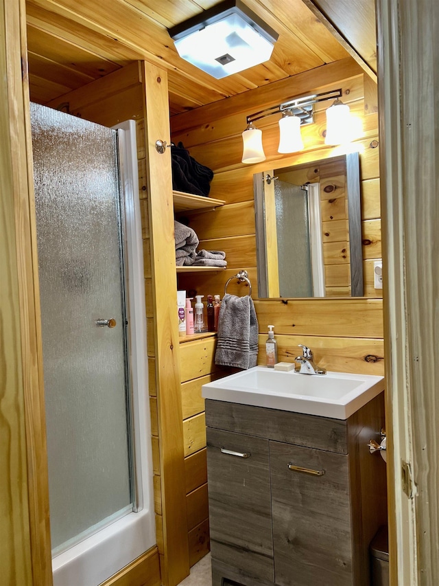 bathroom with wooden walls, a shower stall, and vanity