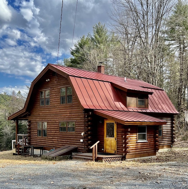 cabin featuring log exterior, a chimney, a standing seam roof, and metal roof