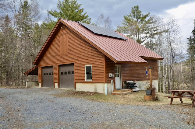 view of property exterior with solar panels, a detached garage, a standing seam roof, and metal roof