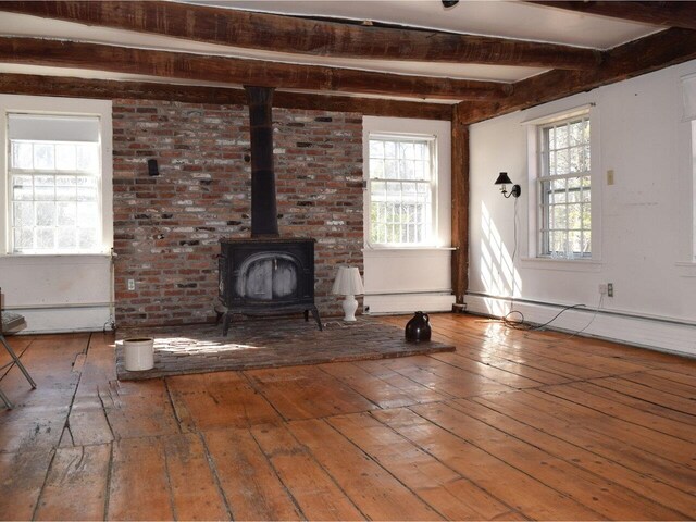 1419 Stonebridge Rd, Georgia, VT 05468 - unfurnished living room featuring beamed ceiling, hardwood / wood-style flooring, a wood stove, and a healthy amount of sunlight