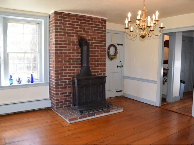 1419 Stonebridge Rd, Georgia, VT 05468 - unfurnished living room featuring an inviting chandelier, a wood stove, wood-type flooring, baseboards, and a baseboard radiator