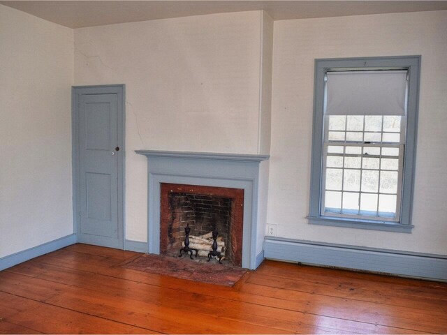 1419 Stonebridge Rd, Georgia, VT 05468 - unfurnished living room featuring a baseboard heating unit, hardwood / wood-style flooring, baseboards, and a fireplace with flush hearth