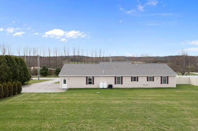back of property with fence, a lawn, and a shingled roof