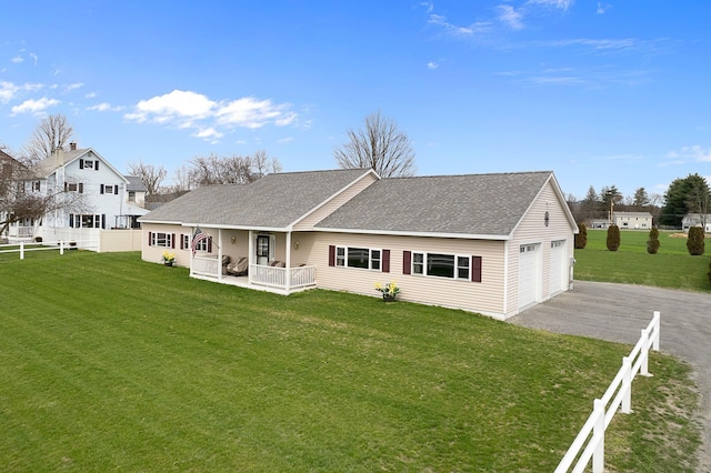 rear view of property with fence, a yard, a shingled roof, and a garage