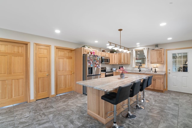 kitchen featuring light stone counters, stainless steel appliances, a sink, a kitchen island, and a kitchen bar