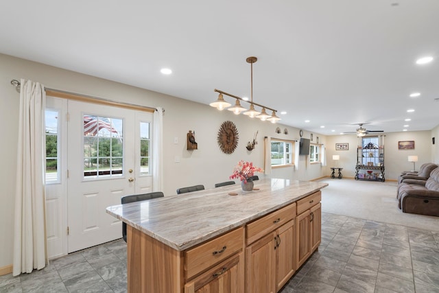 kitchen featuring open floor plan, recessed lighting, a ceiling fan, decorative light fixtures, and a kitchen island