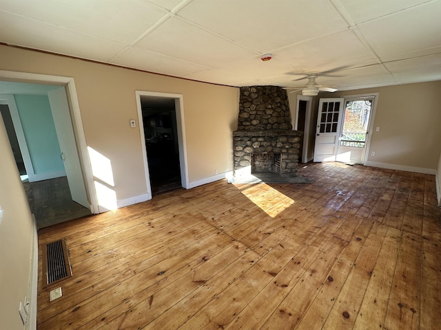 unfurnished living room with wood-type flooring, visible vents, a ceiling fan, and baseboards