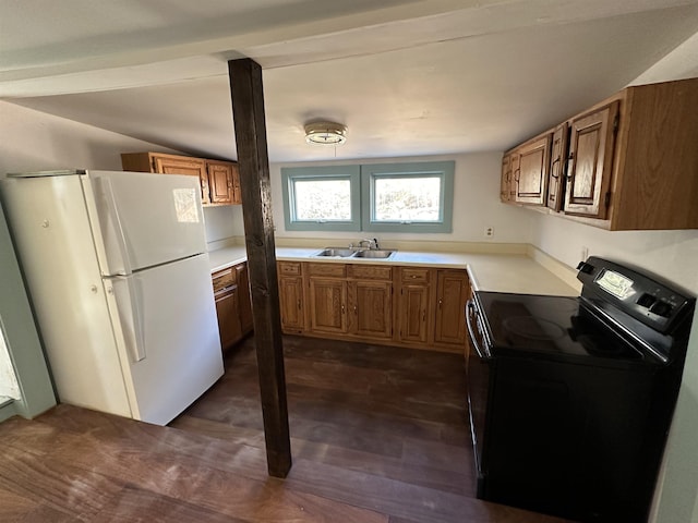 kitchen featuring a sink, brown cabinetry, light countertops, black range with electric stovetop, and freestanding refrigerator