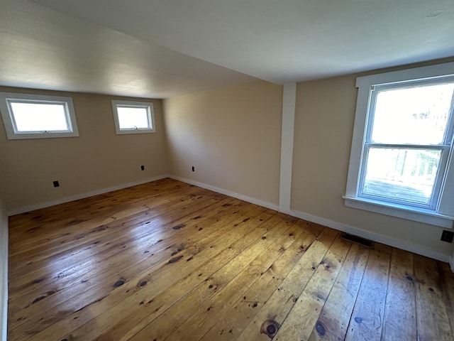 empty room featuring hardwood / wood-style floors, baseboards, and visible vents