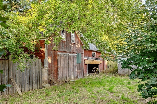 view of barn with a lawn and fence