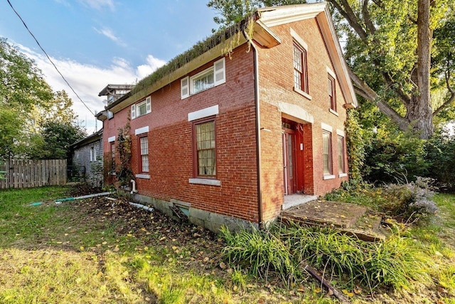 view of side of home with fence and brick siding
