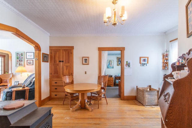 dining room featuring light wood-type flooring, crown molding, baseboards, and an inviting chandelier