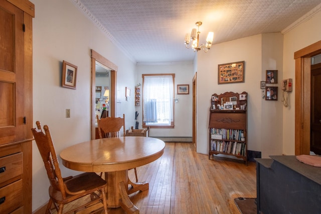 dining room with light wood finished floors, baseboard heating, a chandelier, and ornamental molding