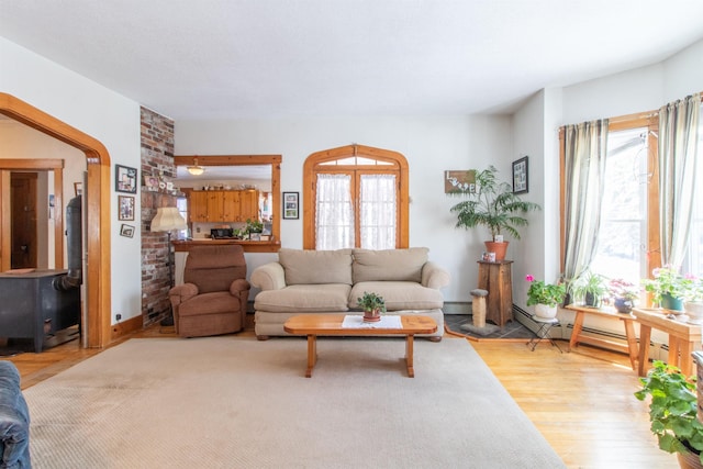 living room with wood finished floors, a wood stove, and baseboard heating