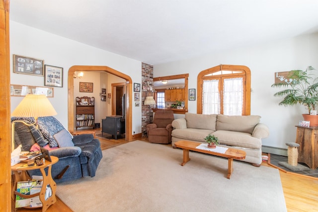 living area with a baseboard heating unit, arched walkways, and wood finished floors