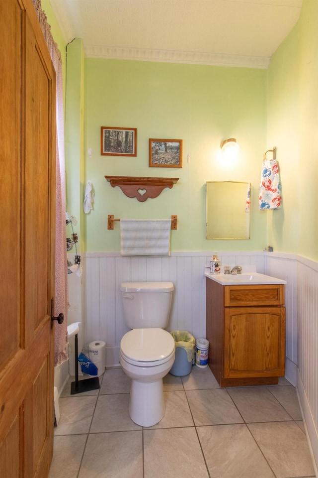 bathroom with wainscoting, toilet, vanity, and tile patterned flooring