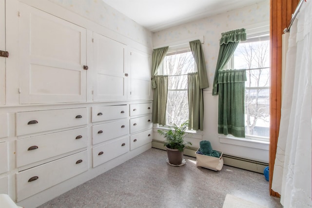 living area featuring a baseboard heating unit and a wealth of natural light
