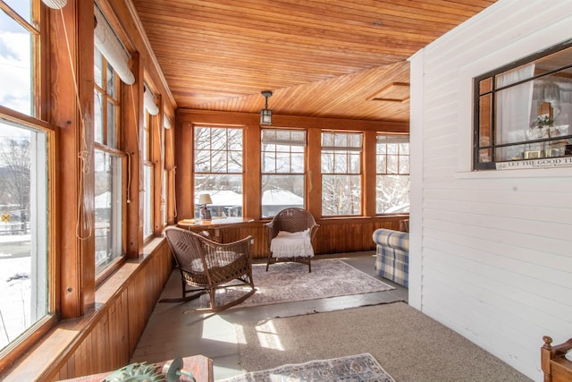 sunroom with wooden ceiling, wood walls, carpet floors, and a healthy amount of sunlight