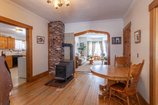 dining room featuring a healthy amount of sunlight, a wood stove, crown molding, and light wood finished floors