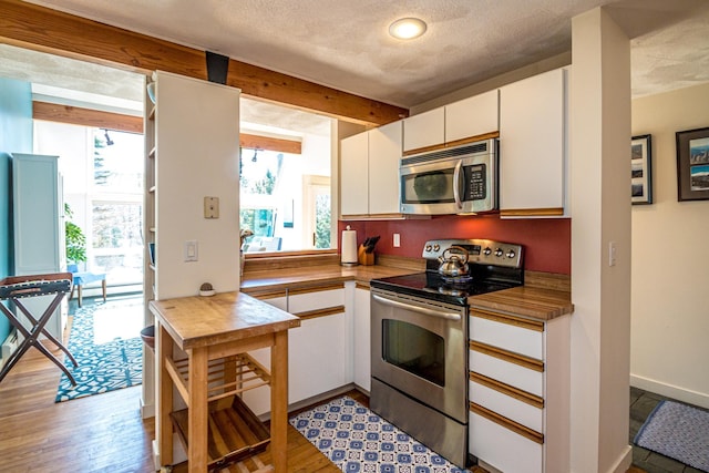 34 Ridge Rd, Jackson, NH 03846 - kitchen featuring appliances with stainless steel finishes, plenty of natural light, white cabinetry, light wood finished floors, and a textured ceiling