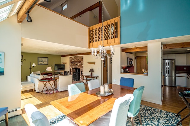 34 Ridge Rd, Jackson, NH 03846 - dining area with a high ceiling, a baseboard radiator, a brick fireplace, wood finished floors, and a chandelier