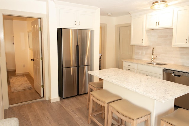 30 Pond St Unit 11, Ludlow, VT 05149 - kitchen featuring light stone counters, a sink, decorative backsplash, stainless steel appliances, and light wood finished floors
