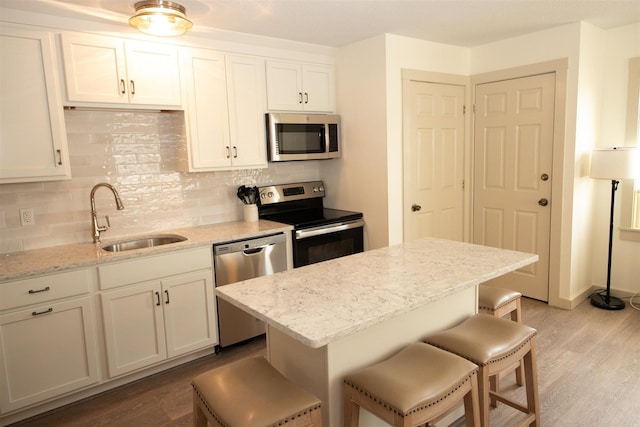 30 Pond St Unit 11, Ludlow, VT 05149 - kitchen featuring a sink, decorative backsplash, light wood-style floors, a breakfast bar, and appliances with stainless steel finishes