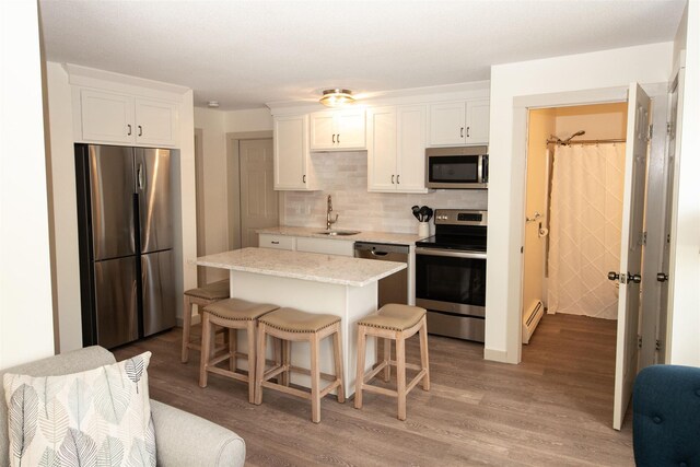 30 Pond St Unit 11, Ludlow, VT 05149 - kitchen featuring stainless steel appliances, a sink, backsplash, light wood-style floors, and white cabinetry