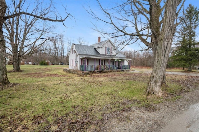 view of front facade featuring a chimney, a front yard, and covered porch