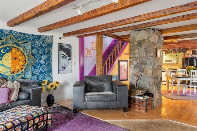living area with beamed ceiling, hardwood / wood-style flooring, and stairs