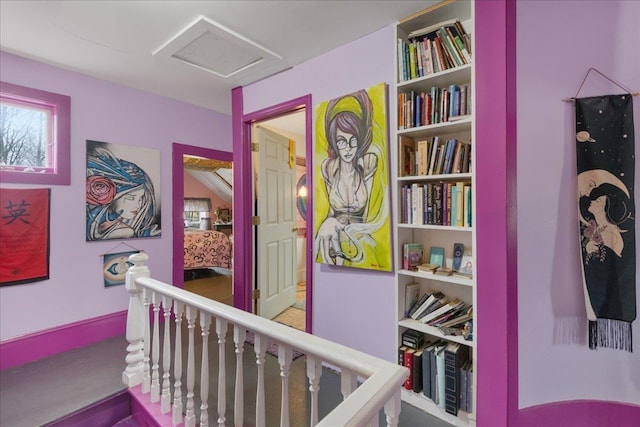 corridor featuring attic access, built in features, and an upstairs landing